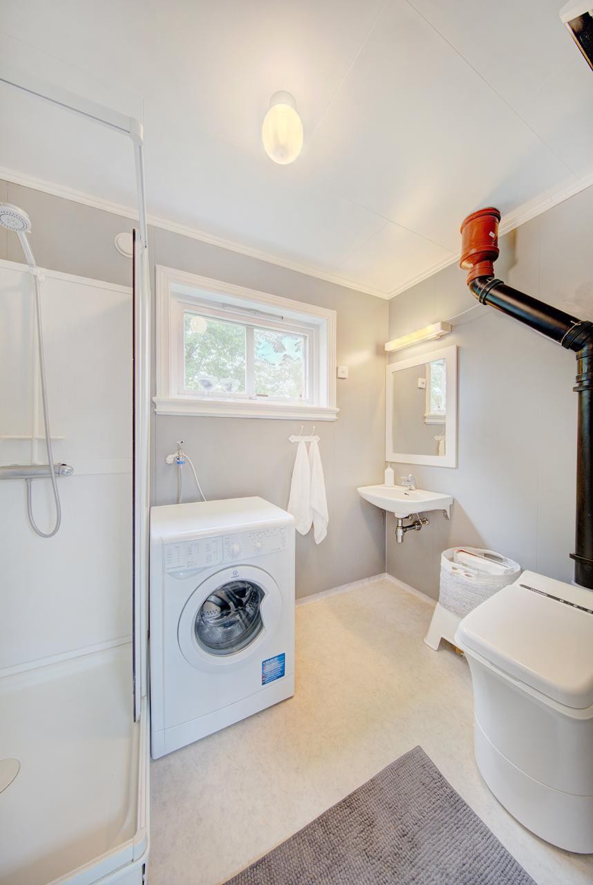 Baderom med dusjkabinett, cinderelle forbrenningstoalett, servant og opplegg for vaskemaskin Galleribilde