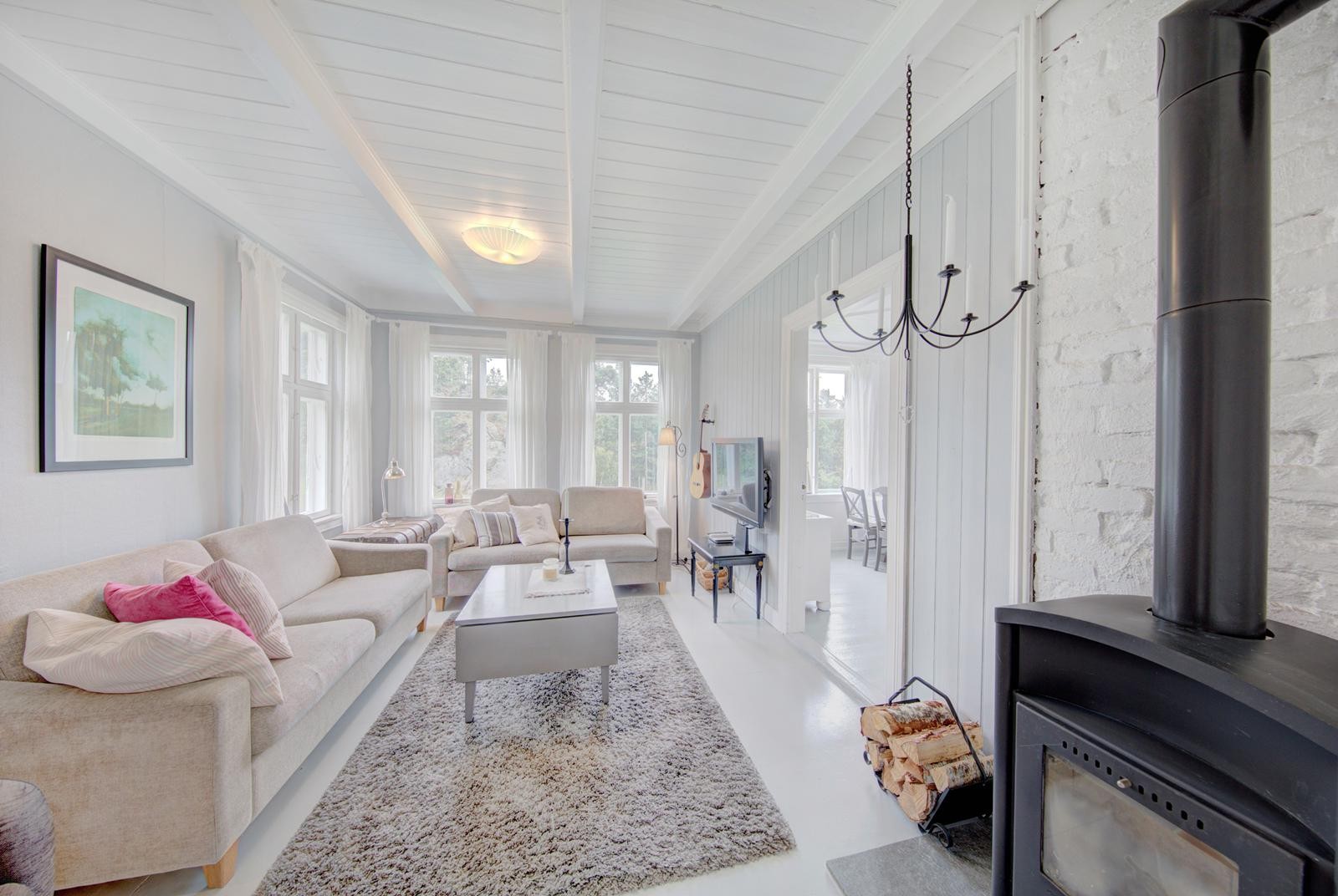 Stue i lyse fine garger og peisovn med innsyn Galleribilde