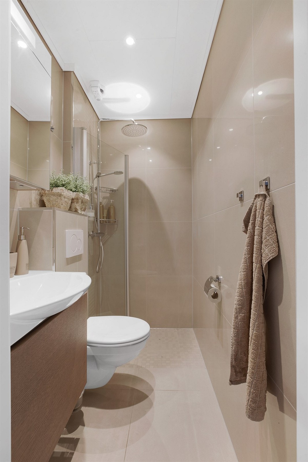 Til høyre for yttergang ligger boligens delikate og helfliset baderom med varmekabler i gulv Galleribilde