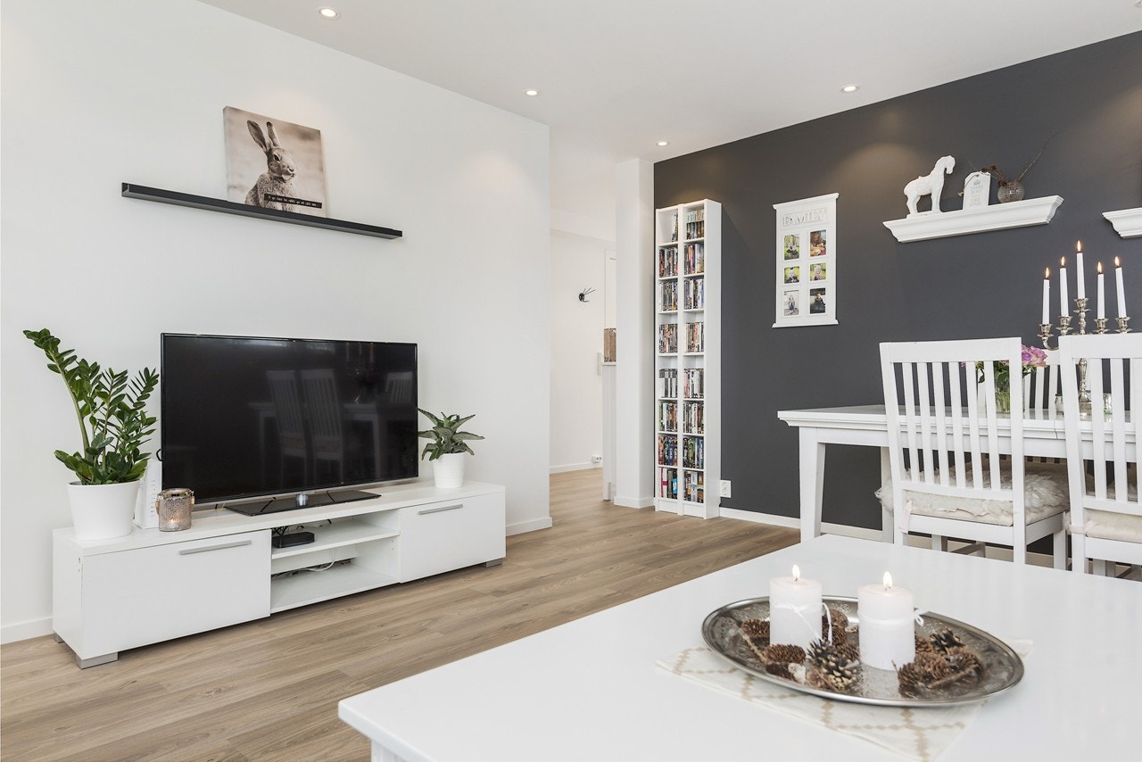 Veggene i stuen er hovedsakelig holdt i lys nyanse, med unntak av en mørk fondvegg som gir rommet dybde Galleribilde