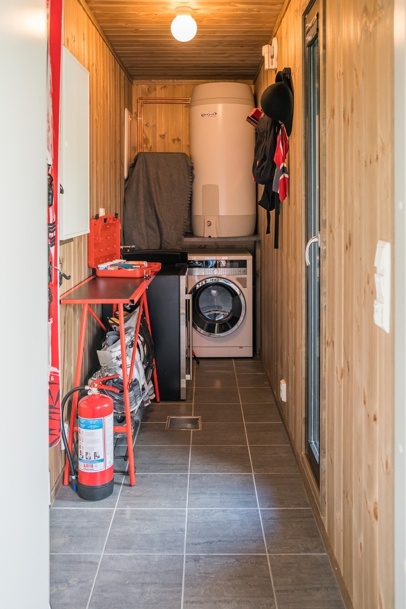 Ved siden av hovedinngangen har man adkomst til en flislagt bod med varmekabler i gulvet. Boden er utstyrt med opplegg for vaskemaskin og egner seg fint som smørebord. Hyttens varmtvannsbereder på 198 liter er plassert i boden. Galleribilde