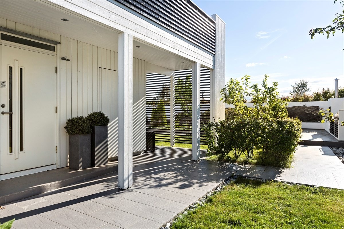 Inngangsparti er overbygd. Pen adkomst med plen og flis. Galleribilde