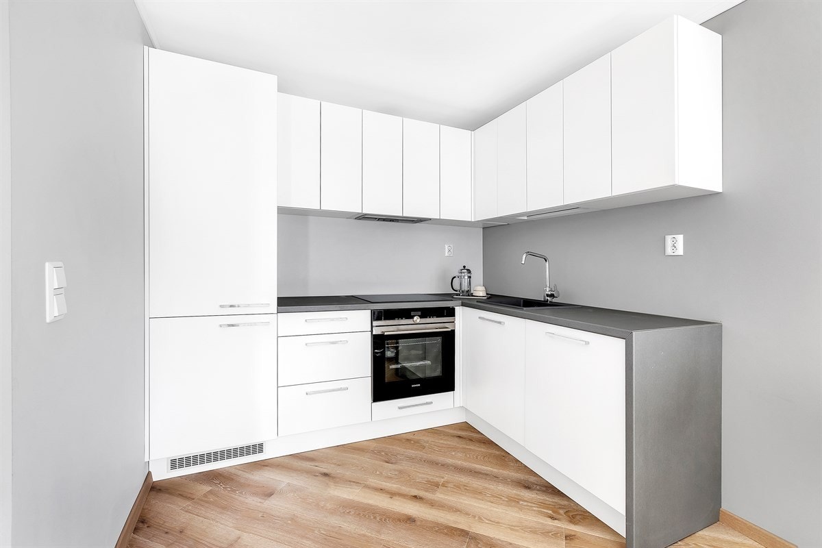 Kjøkken med lys og moderne innredning, integrert stekeovn og kjøl/frys. Galleribilde