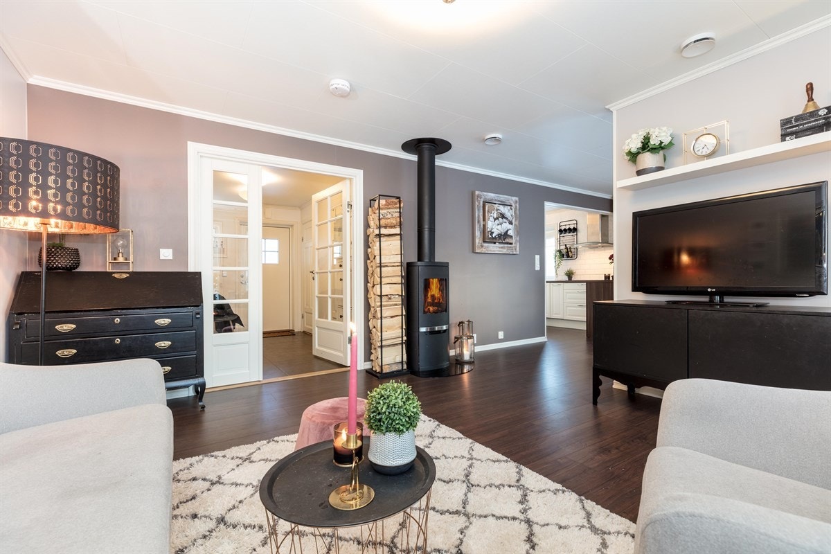 Stuen har malte slette overflater og flott slitesterk laminat på gulv med herlig underliggende gulvvarme. Midt i rommet er det montert en moderne peisovn, som gir en god atmosfære, varme og hygge til rommet. Galleribilde