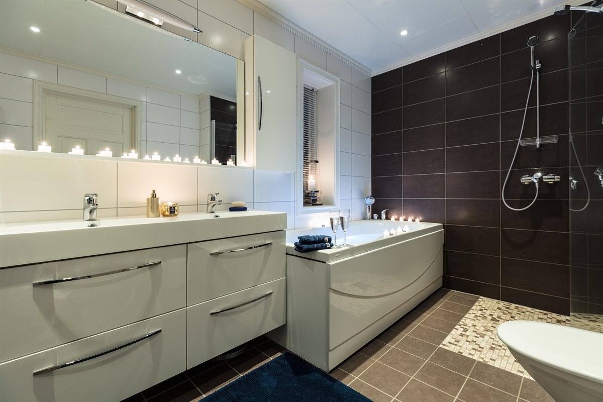 Videre har badet et frittstående toalett og dusjnisje med 2 stk. hånddusjer, PVC sluk og glassdør. Det er lagt mosaikkfliser på gulv i dusjsonen. Galleribilde