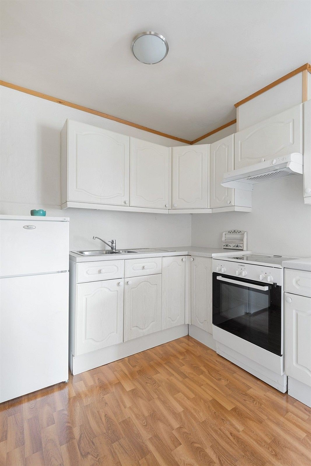 Åpen kjøkkenstueløsning med komfyr, kjøleskap og oppvaskmaskin. Galleribilde