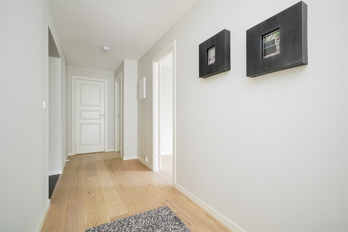 Entreen gir et godt førsteinntrykk av leiligheten og er pent innredet med mørke fliser på gulv, behagelig gulvvarme og hvite, slette vegger. Galleribilde