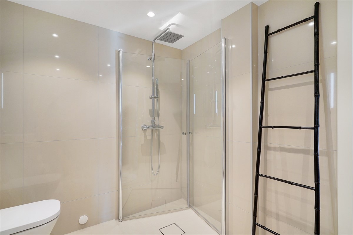 . Innredningen består av en frittstående servant på en praktisk skuffeløsning med topplate i tre, et veggmontert toalett og opplegg for vaskemaskin. Galleribilde