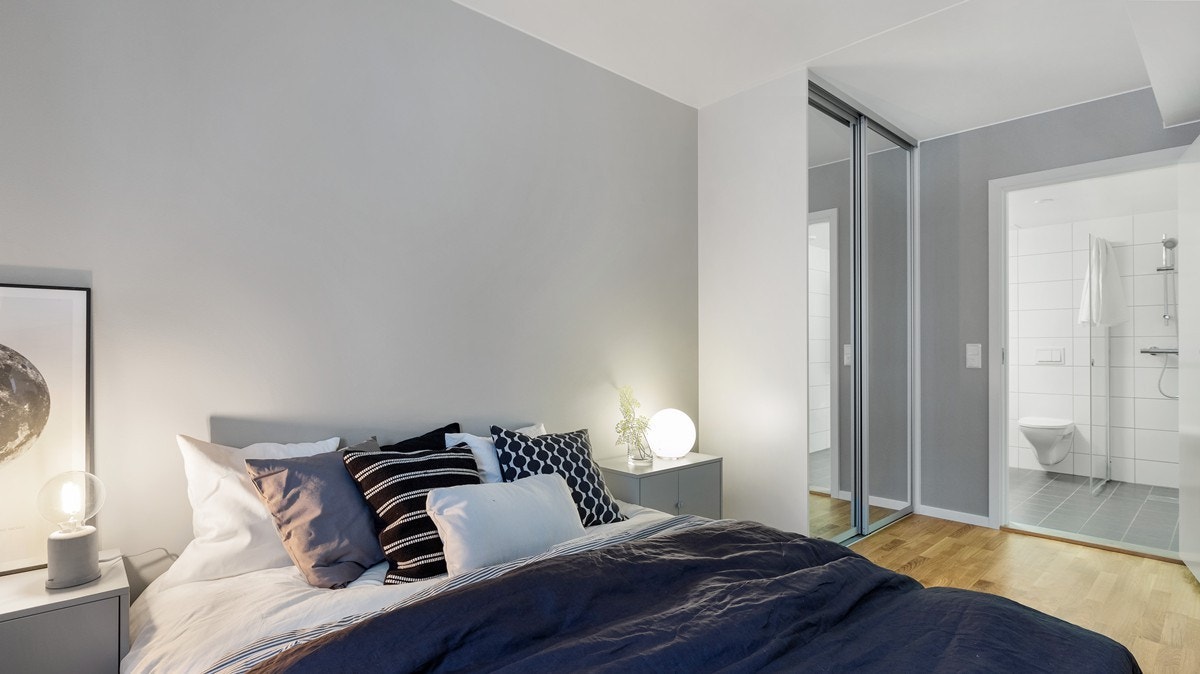 Romslig soverom med skyvedørsgarderobe med speilfronter og adkomst til bad Galleribilde