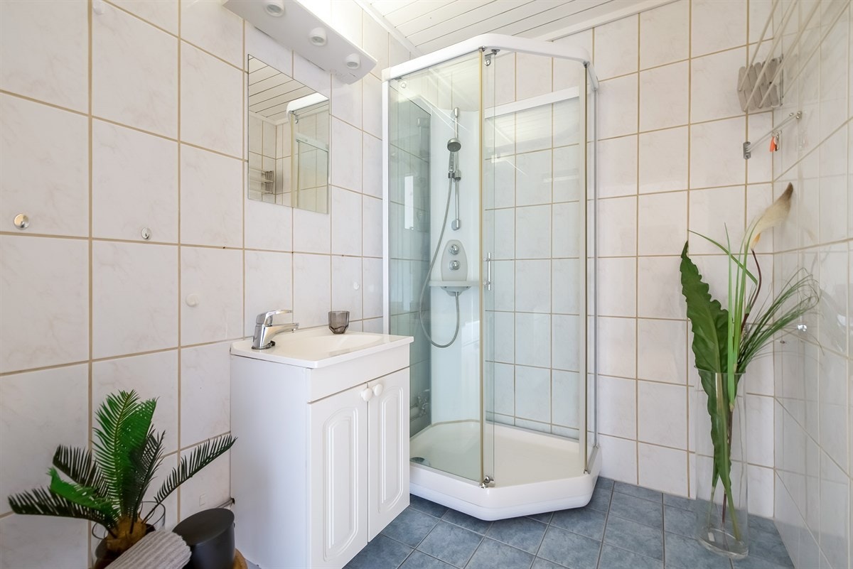 Flislagt bad med varmekabler. Servant med skapinnredning og speil. Galleribilde