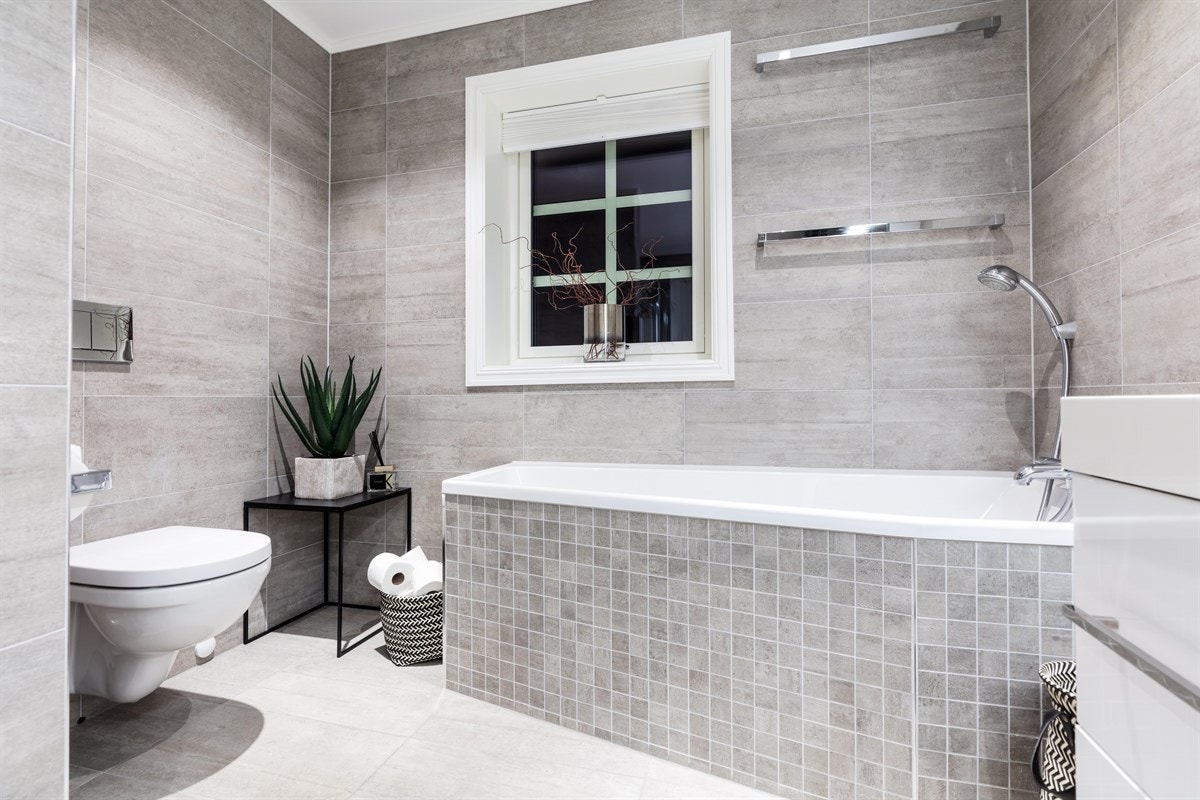 Badet i andre etasje ligger i soveromsgangen og fremstår som en liten velværeavdeling. Også her er det flislagte overflater, integrerte downlights i himling og varme i gulvet. I tillegg er det innfliset badekar og en herlig dusjsone med to dusjer. Galleribilde