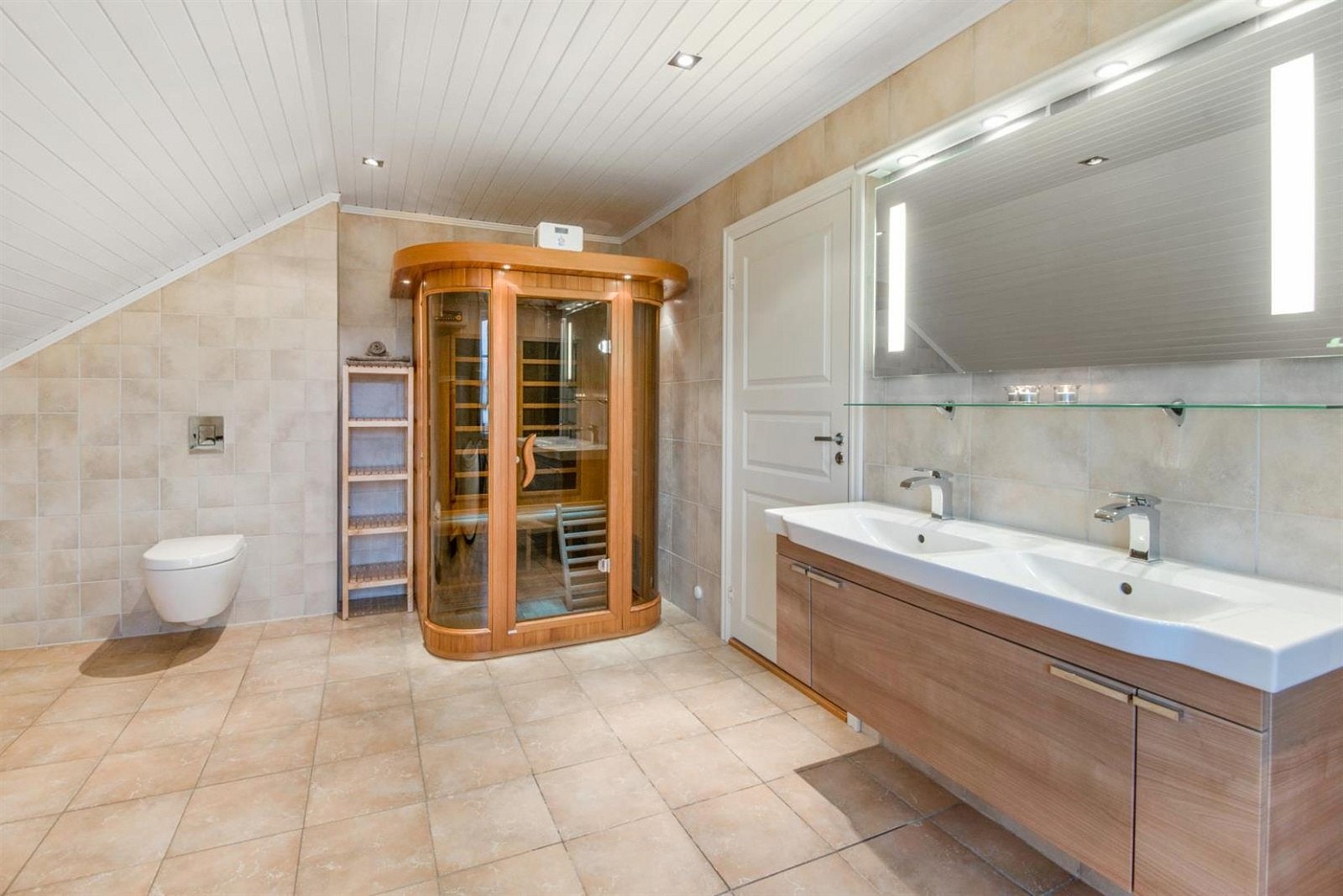Badet har flotte detaljer som infrarød badstue, veggmontert toalett, dobbelt boblebadekar, samt et stort dusjhjørne med innfellbare glassdører og mosaikkfliser på vegger i dusjsonen. Galleribilde