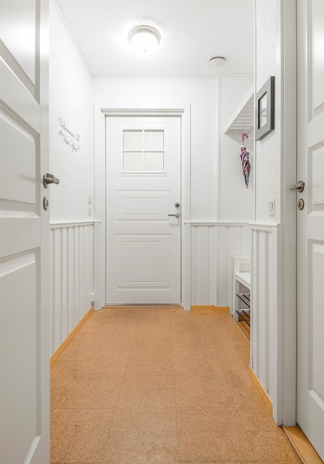 Entreen har korkfliser på gulv, vegger i hvitt med brystningspanel og åpen garderobeløsning i form av hylle med klesstang. Galleribilde