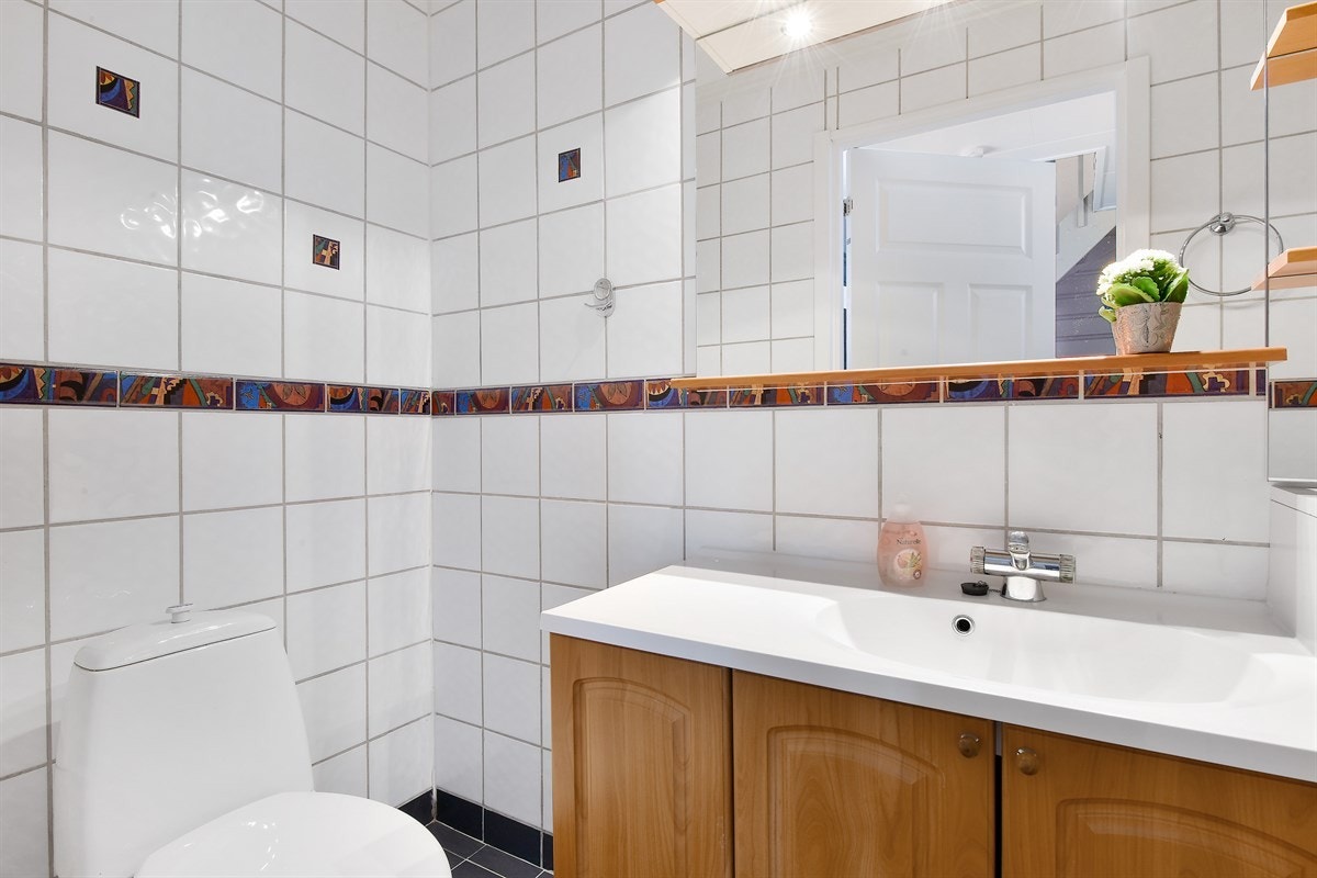 Badet er utstyrt med fliser på gulv og vegger, varmekabler og elektrisk avtrekksvifte. Galleribilde