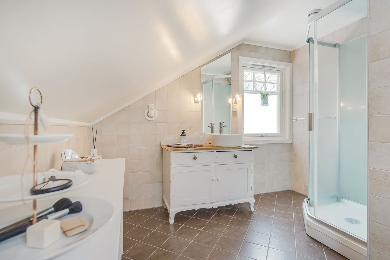 Det innbydende badet er utstyrt med vegghengt wc, dusjkabinett og skålservant på et sjarmerende gammelt skap Galleribilde