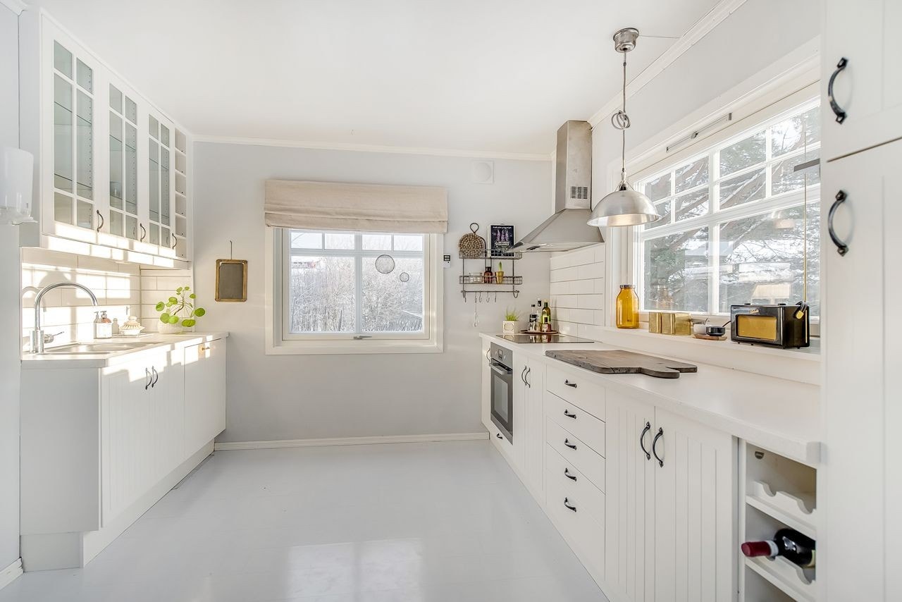 Lyst og trivelig kjøkken. Pen Ikea innredning med integrerte hvitevarer. Lyse fliser mellom benk og overskap Galleribilde