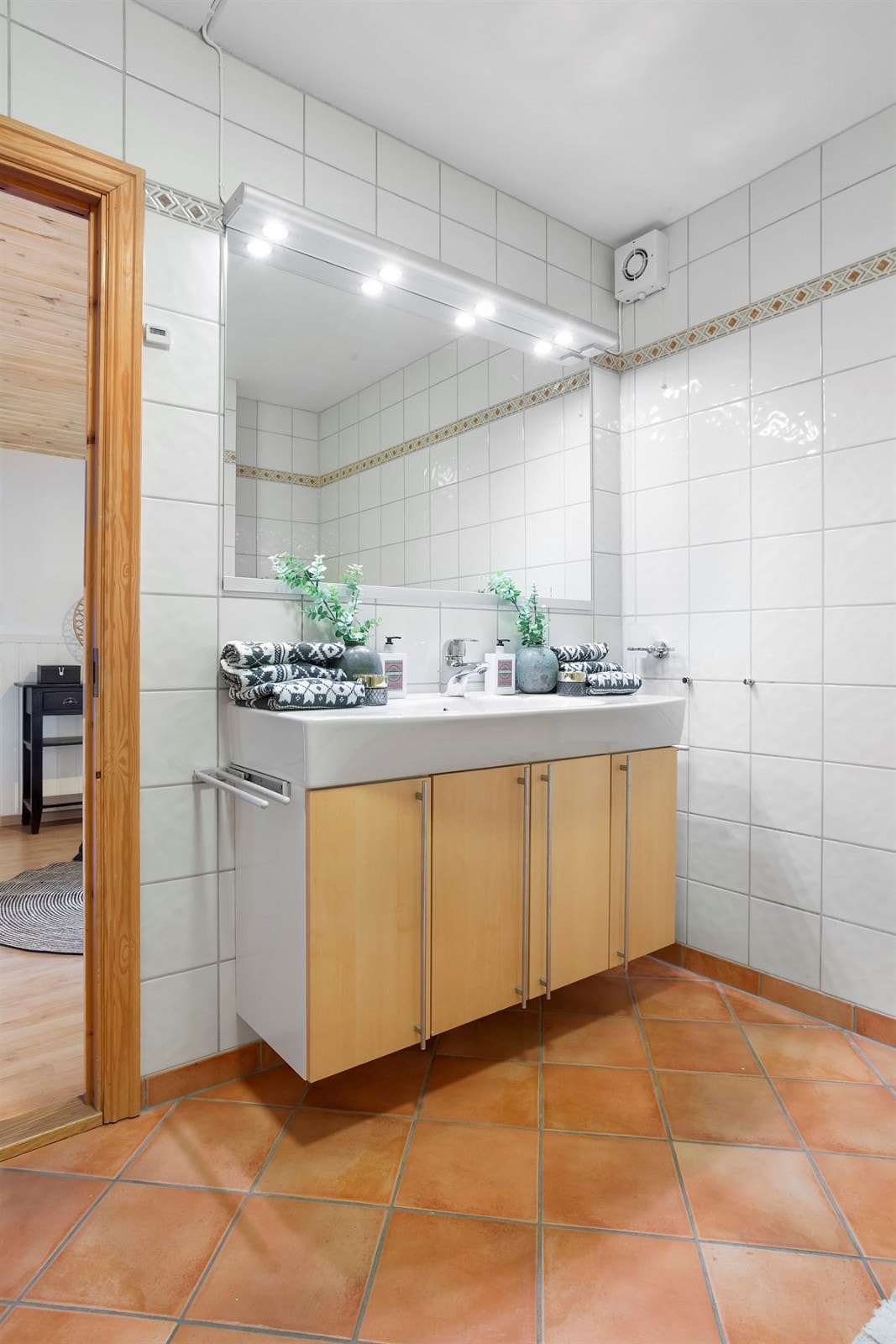 Badet er utstyrt åpen dusjplass med dusjhjørne, vegghengt toalett og heldekkende servant i skapinnredning. Galleribilde