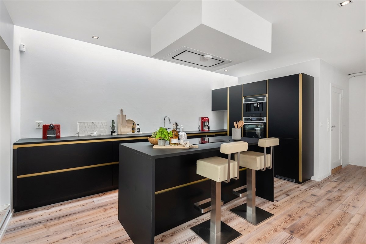 Stort kjøkken med spiseplass. Moderne kjøkkeninnredning med sorte matte fronter Galleribilde