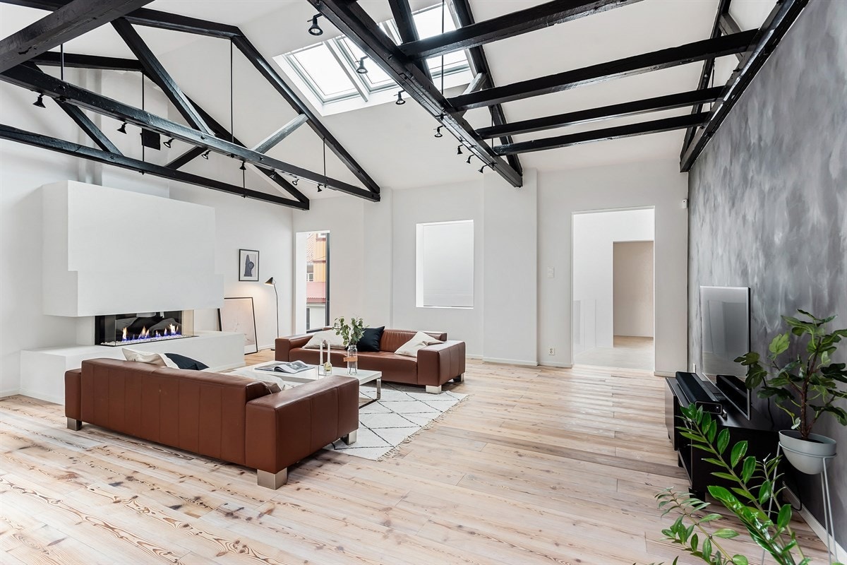 Stor peisestue med detaljer som svært god takhøyde, takvinduer, synlige takbjelker og en flott gasspeis Galleribilde