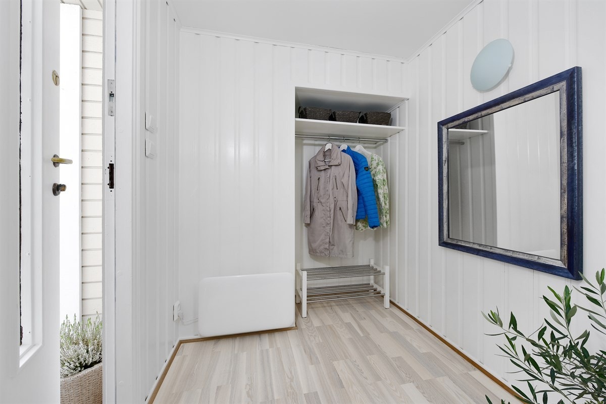 Entreen er innbydende med parkettgulv fra 2017/18, hvitmalte panelvegger og en praktisk, åpen garderobenisje, som er innredet med hylle og stang for oppheng. Galleribilde