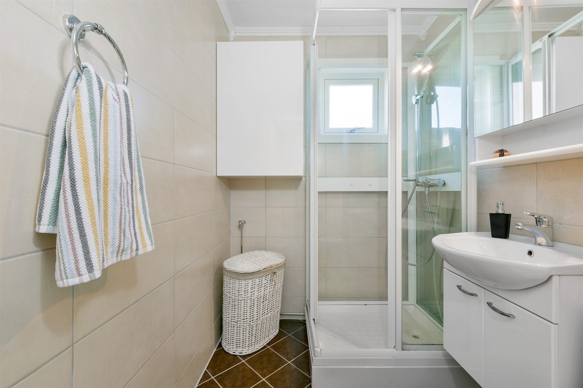 Badet fremstår med et smakfullt og tidsmessig preg. Det er brune fliser på gulv og lyse fliser på vegg. Galleribilde