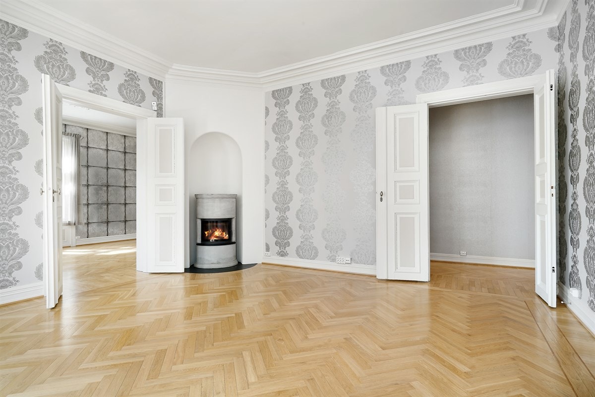 Leilighet 1. etasje. Veggene har medaljongtapet i en lys gråtone, gulvet har parkett i fiskebeinsmønster og de doble fløydørene har gråmalte speil. Galleribilde