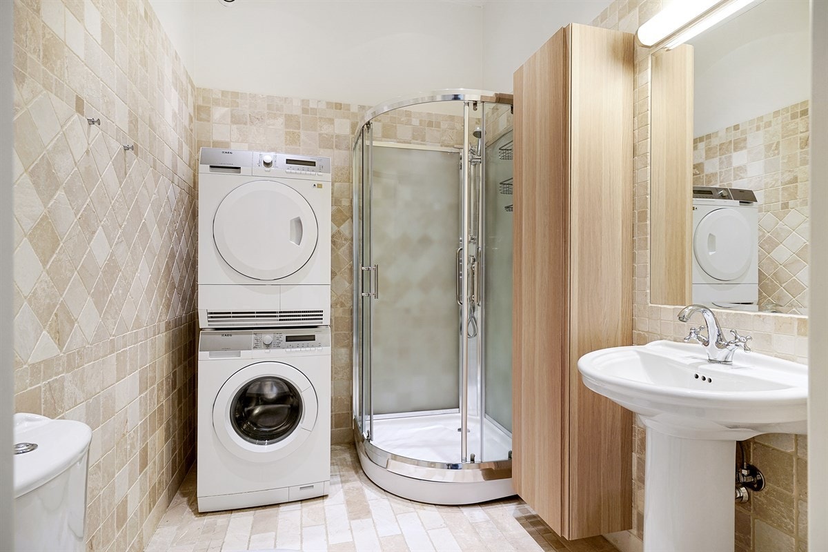 Leilighet 2. etasje. Dusjbadet har samme fliser, gulvvarme og downlights. Rommet har søyleservant, speil med overlys, dusjkabinett og toalett. Dette badet har opplegg for vaskesøyle. Galleribilde