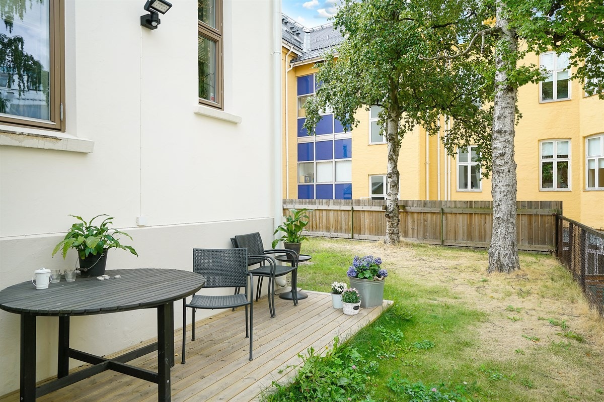 Bakhagen ligger skjermet av et tett gjerde og har godt med boltreplass, rom for lekeapparater og fin plass for ulike møbelgrupper under trærne. I det ene hushjørnet er det laget en markterrasse. Galleribilde