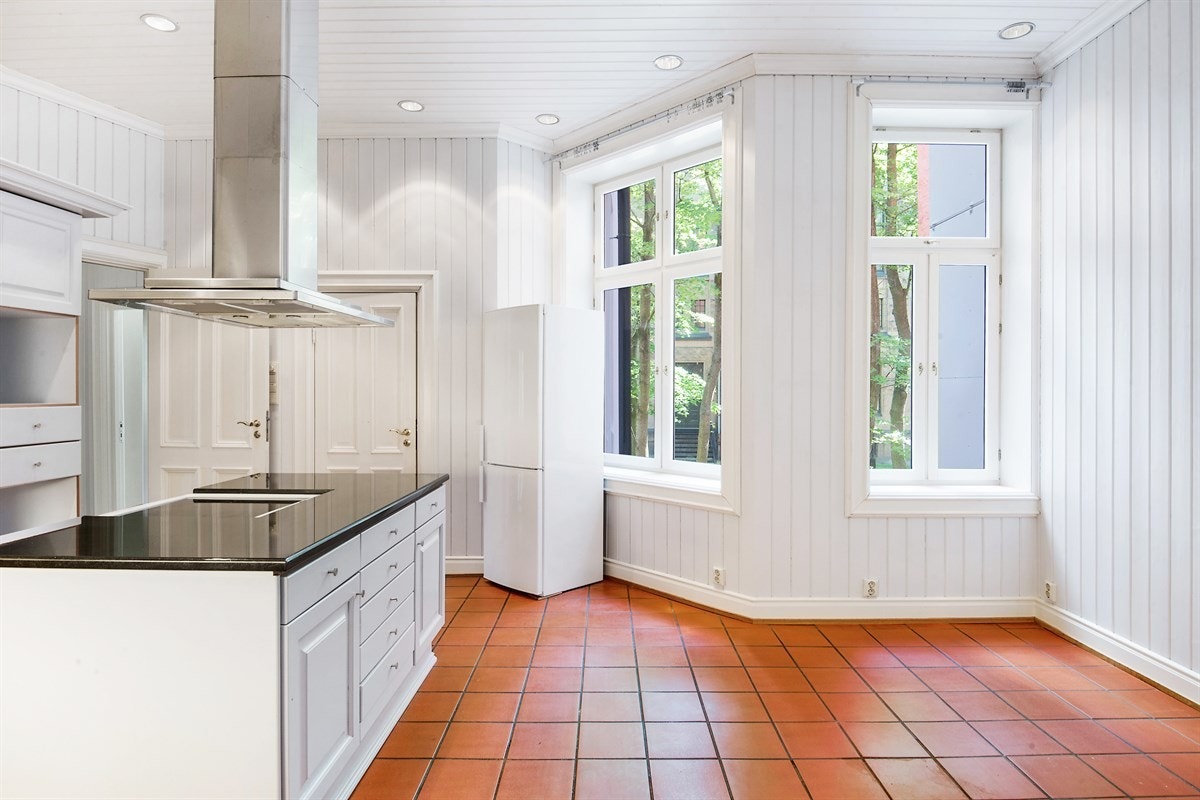 Kjøkkenet er stort og trivelig, med fliser på gulv, gulvvarme og downlights. Rommet har også egen spiseplass og en stemningsfull peis med innsats Galleribilde