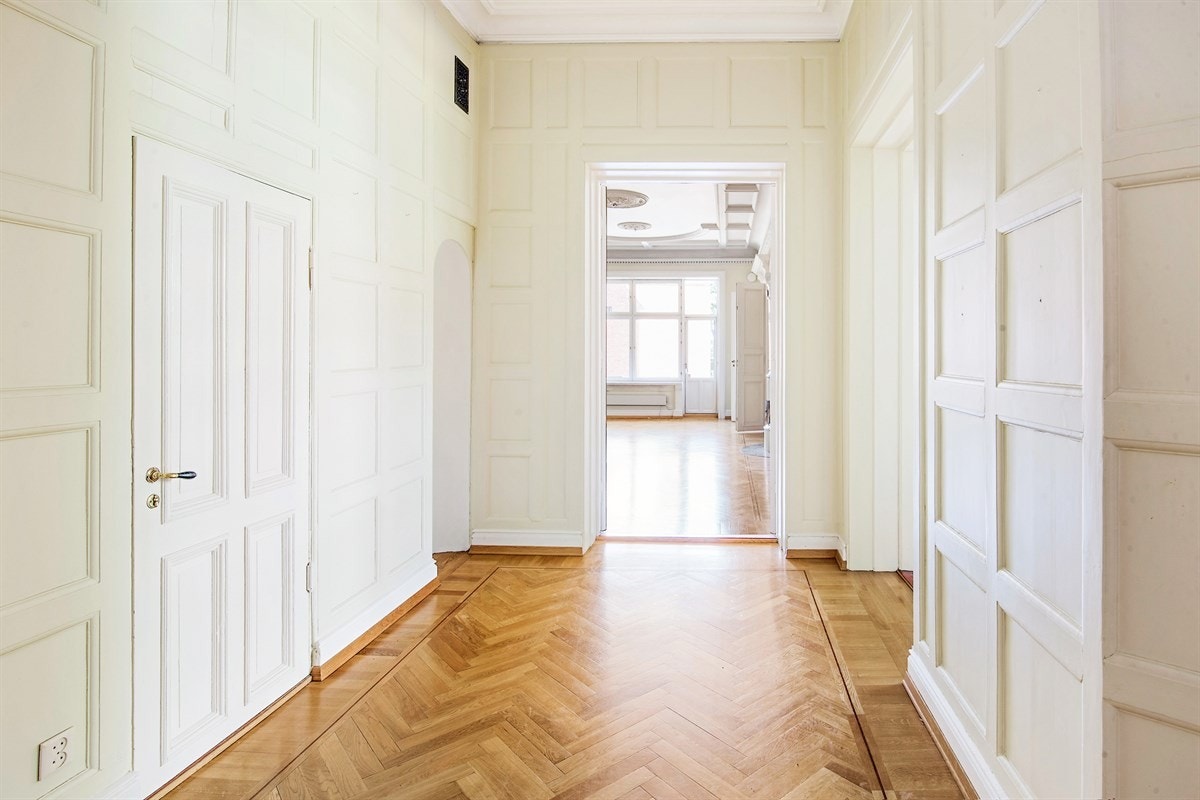 Entreen med en enorm takhøyde, profilerte paneldetaljer, boligens fordums prakt. Galleribilde