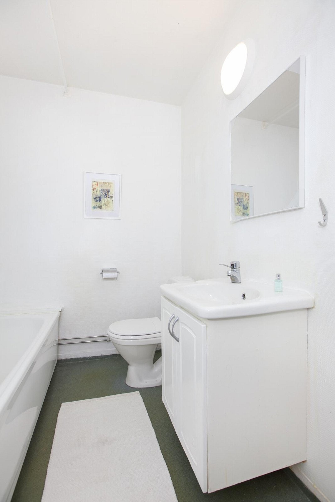 Baderom med badekar m/dusj, klosett og innredning med servant. Badet har behov for renovering. Galleribilde