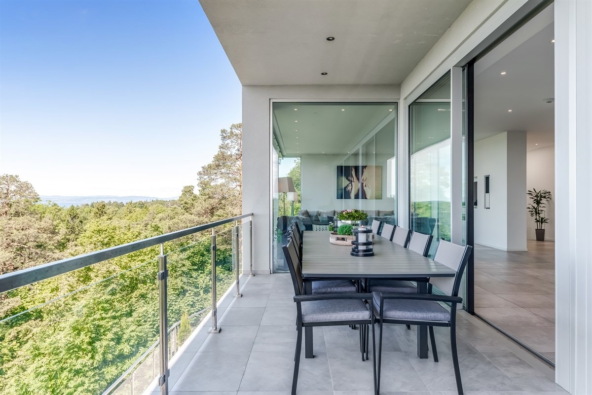 Balkonggulvet har fliser og varmekabler og det er glassrekkverk. Galleribilde