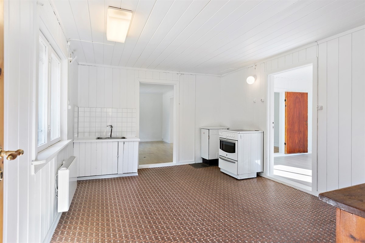 Innredningen er av eldre dato med benk- og overskap i heltre, glatte fronter og heltre benkeplate med enkel nedfelt kum i stål. Det er for øvrig plass til komfyr og kjøleskap i rommet. Galleribilde