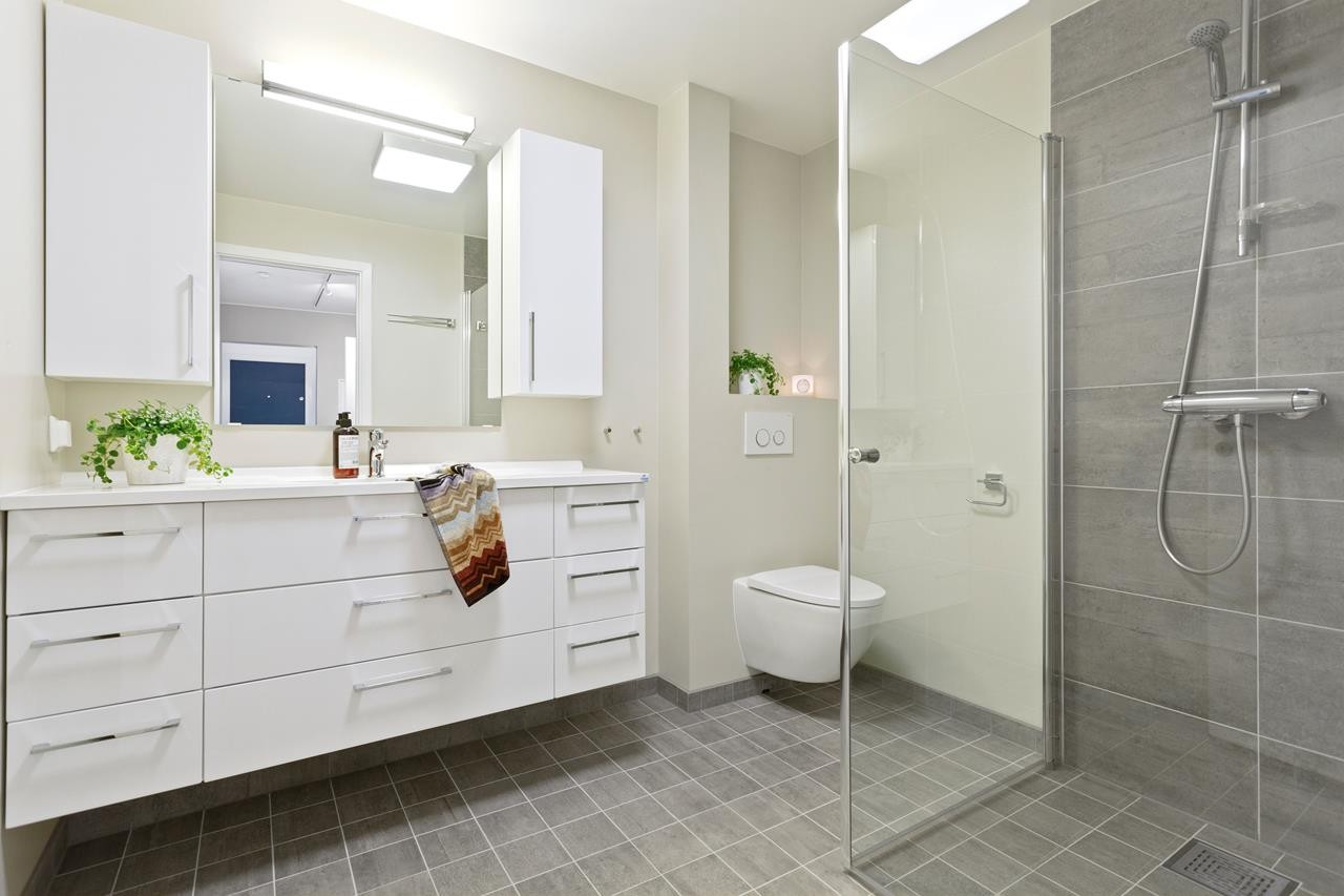 Pent og moderne flislagt baderom som ble totalrenovert i 2014. Dusjhjørne med foldbare glassdører, servantskap, innebygget vegghengt toalett, varmekabler m.m. Galleribilde