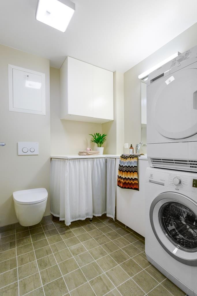 Pent og moderne bad nr 2 / vaskerom / wc med flislagt gulv, vegghengt wc, arbeidsbenk samt opplegg for vaskemaskin og tørketrommel Galleribilde