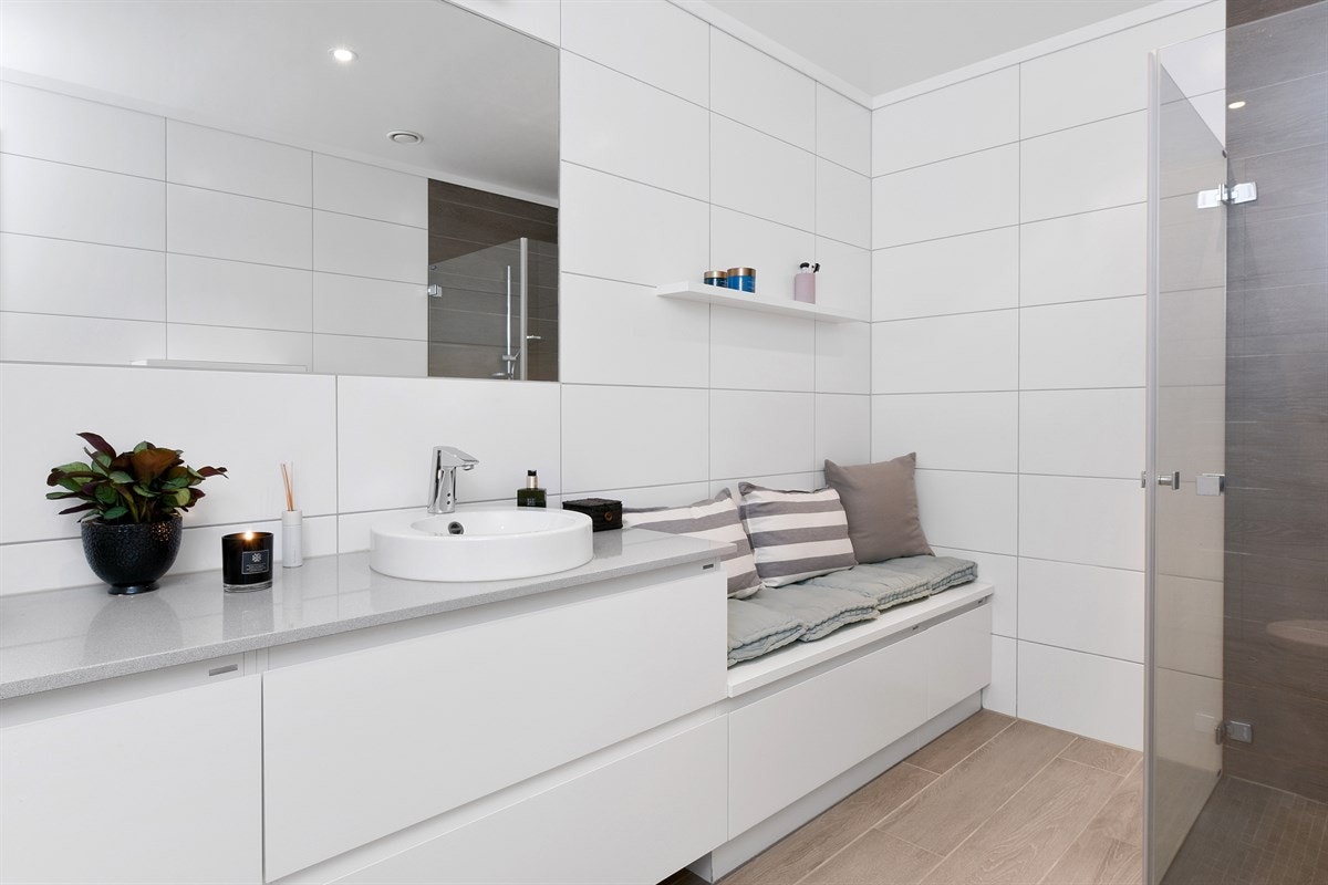 Rommet har også gulvvarme, veggmontert toalett og et dusjhjørne med innfellbare glassdører. Galleribilde