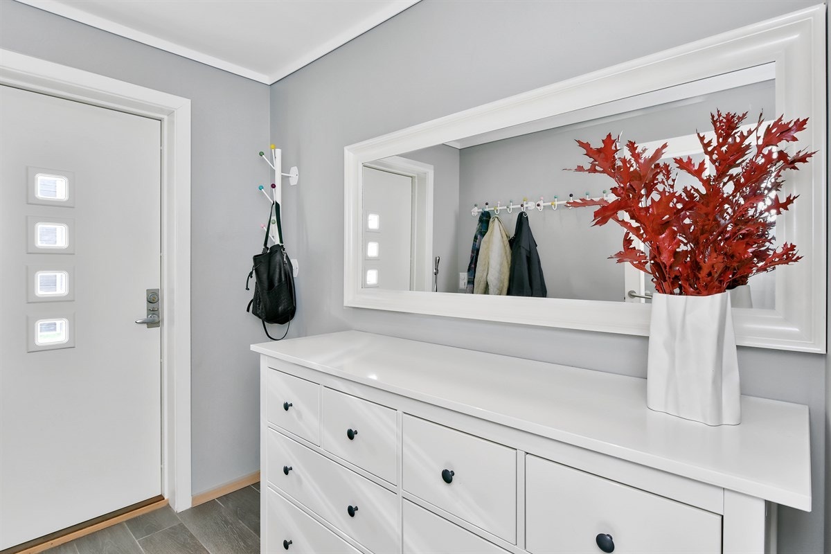 Boligens inngangsparti er i underetasjen, og her ønskes du velkommen av en innbydende entré med grå fliser på gulv, lysmalte vegger, lun gulvvarme og downlights. Galleribilde
