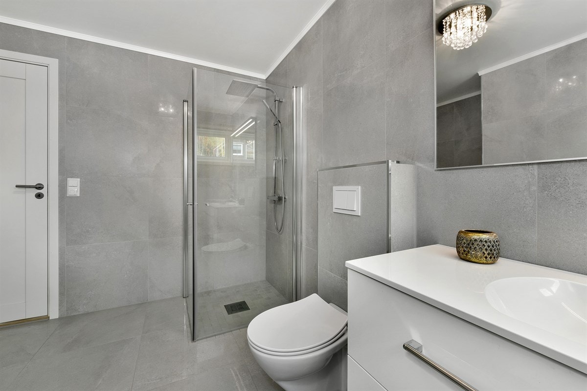 Badet ligger i første etasje og er belagt med store, lysegrå fliser på gulv og vegger. Galleribilde