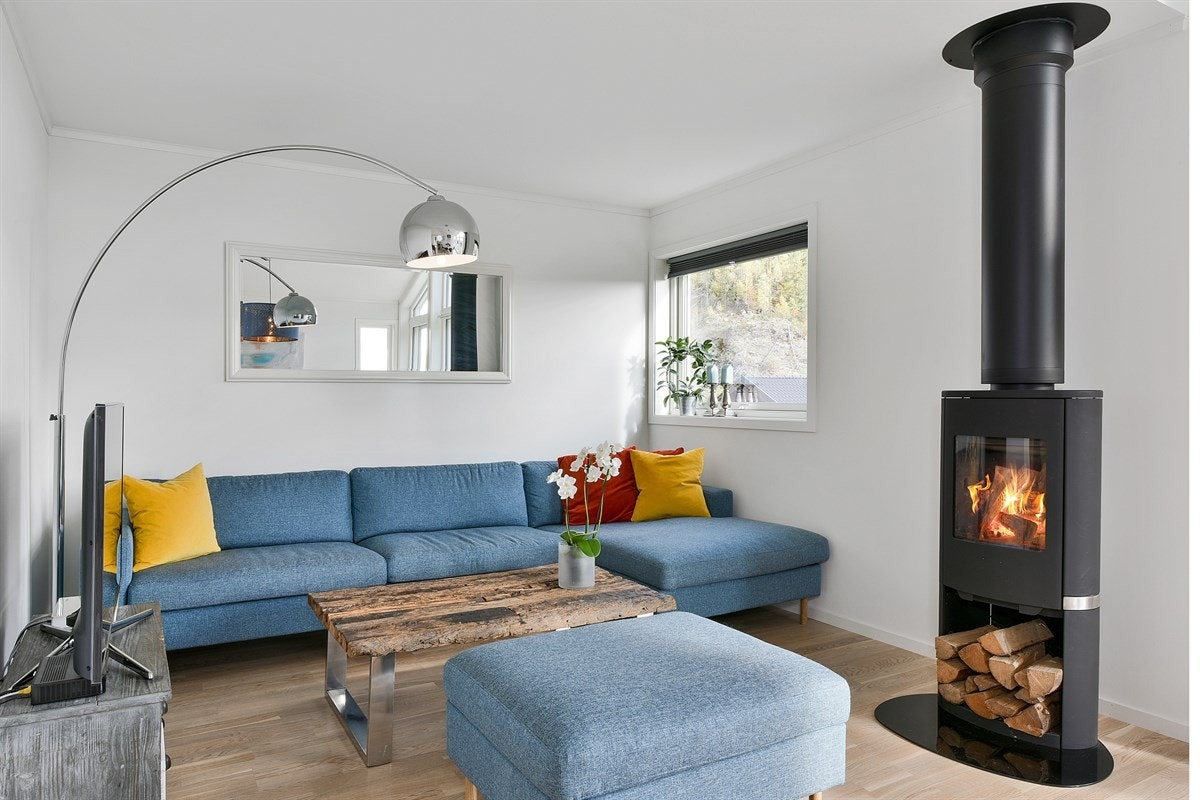 I salongdelen står en moderne peisovn med stålpipe, som bidrar til en hyggelig stemning på mørke høst- og vinterkvelder. Galleribilde