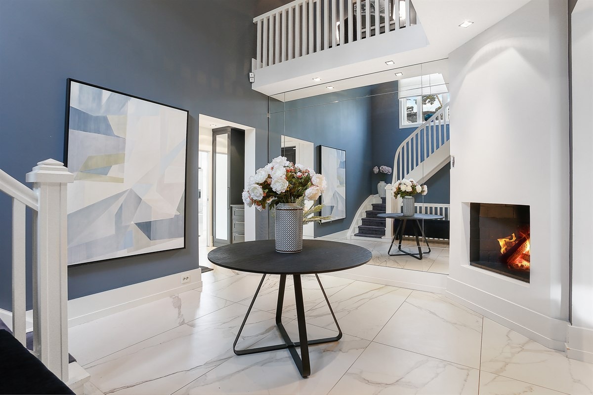 Entreen har hendig tilknytning til toalettrom, samt åpen løsning til flott hall med peis som gir en varm og hyggelig velkomst. Hallen har gulvfliser og downlights fra Deltalight. Galleribilde