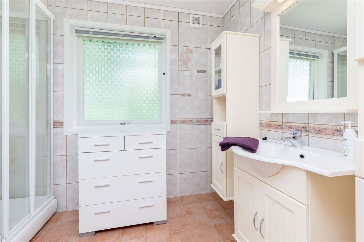 Bad 1 med fliselagt gulv og vegger, dusjkabinett og varmekabler. Galleribilde