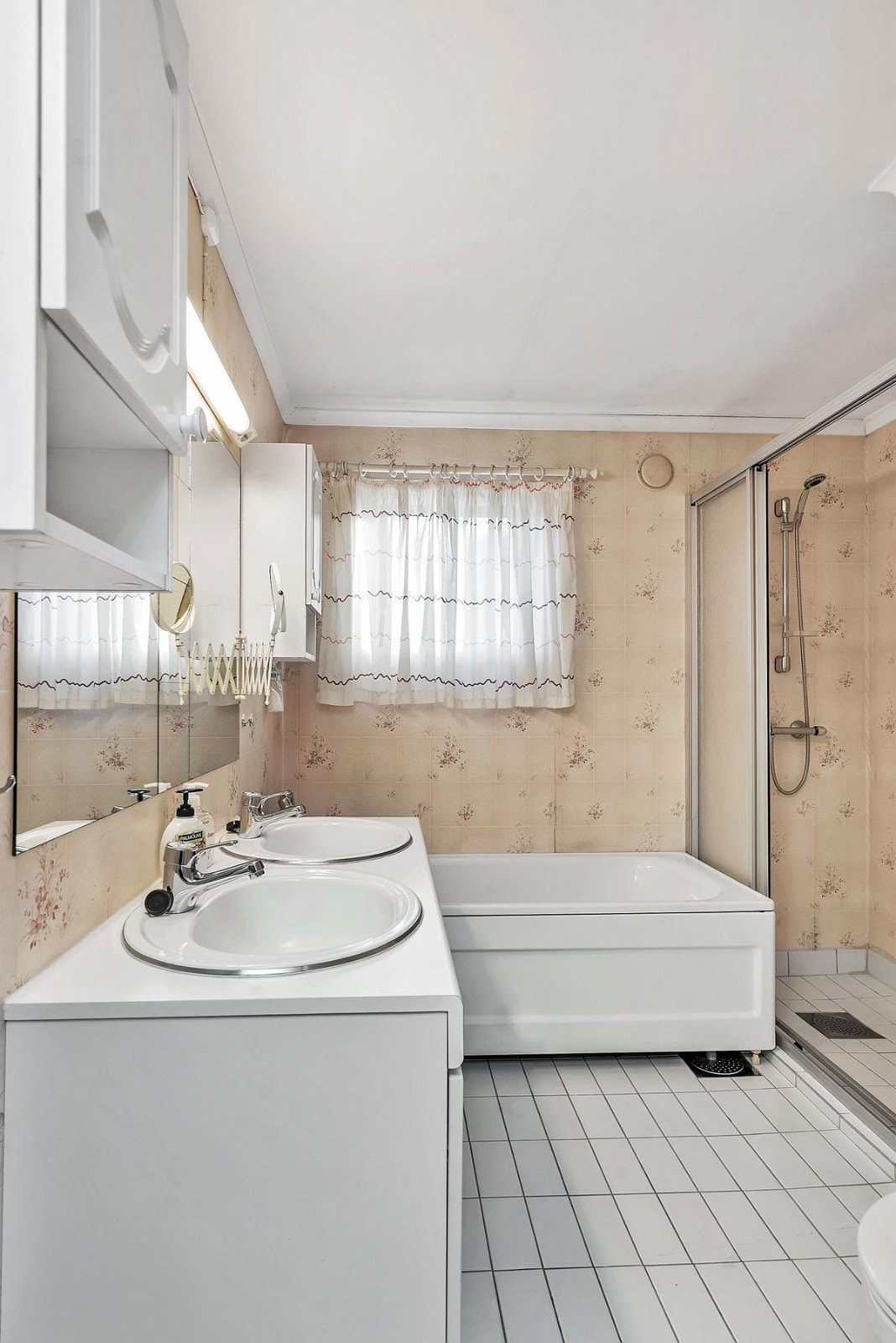 Bad med flislagt gulv og våtromstapet på vgeger. Hvit innredning med dobbel servant. Dusj med skyvedør. Badekar. Wc. Varmekabler. Galleribilde