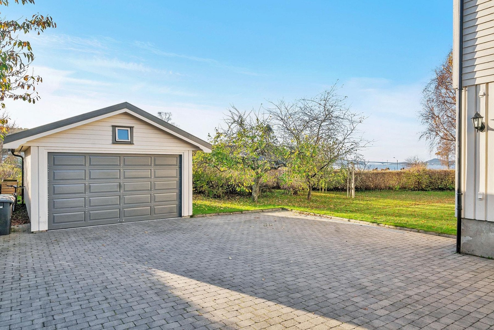 Asfaltert og steinsatt innkjørsel og gårdsplass. Eiendommen har 2 stk garasjer. En frittliggende garasje tatt i bruk 2006, og en garasje bygget sammen med nabo ca.1979. Galleribilde