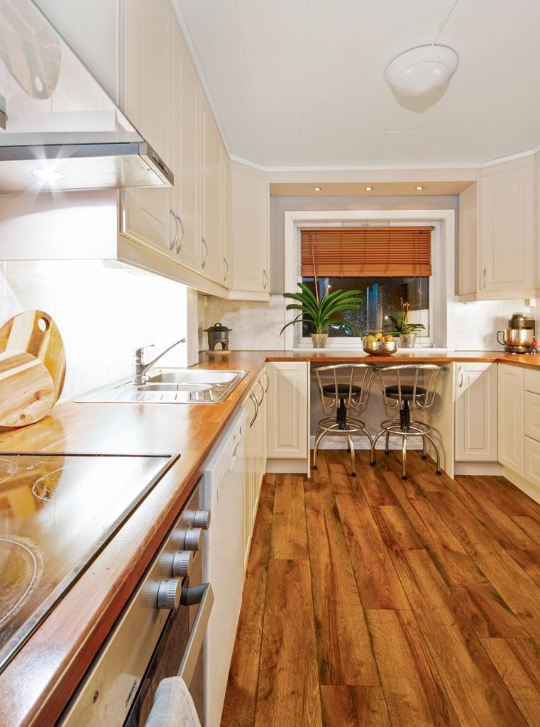 Kjøkkenet har en U-formet innredning med mye skapplass og en hendig spisesplass ved vindu. Galleribilde