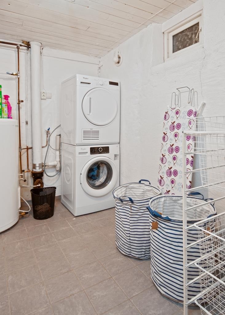 I kjelleren ligger et vaskerom med grå gulvfliser og opplegg for vaskemaskin og tørketrommel. Galleribilde
