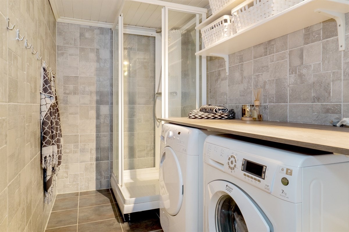 Flislagt bad med dusjkabinett og opplegg for vaskemaskin/tørketrommel. Galleribilde