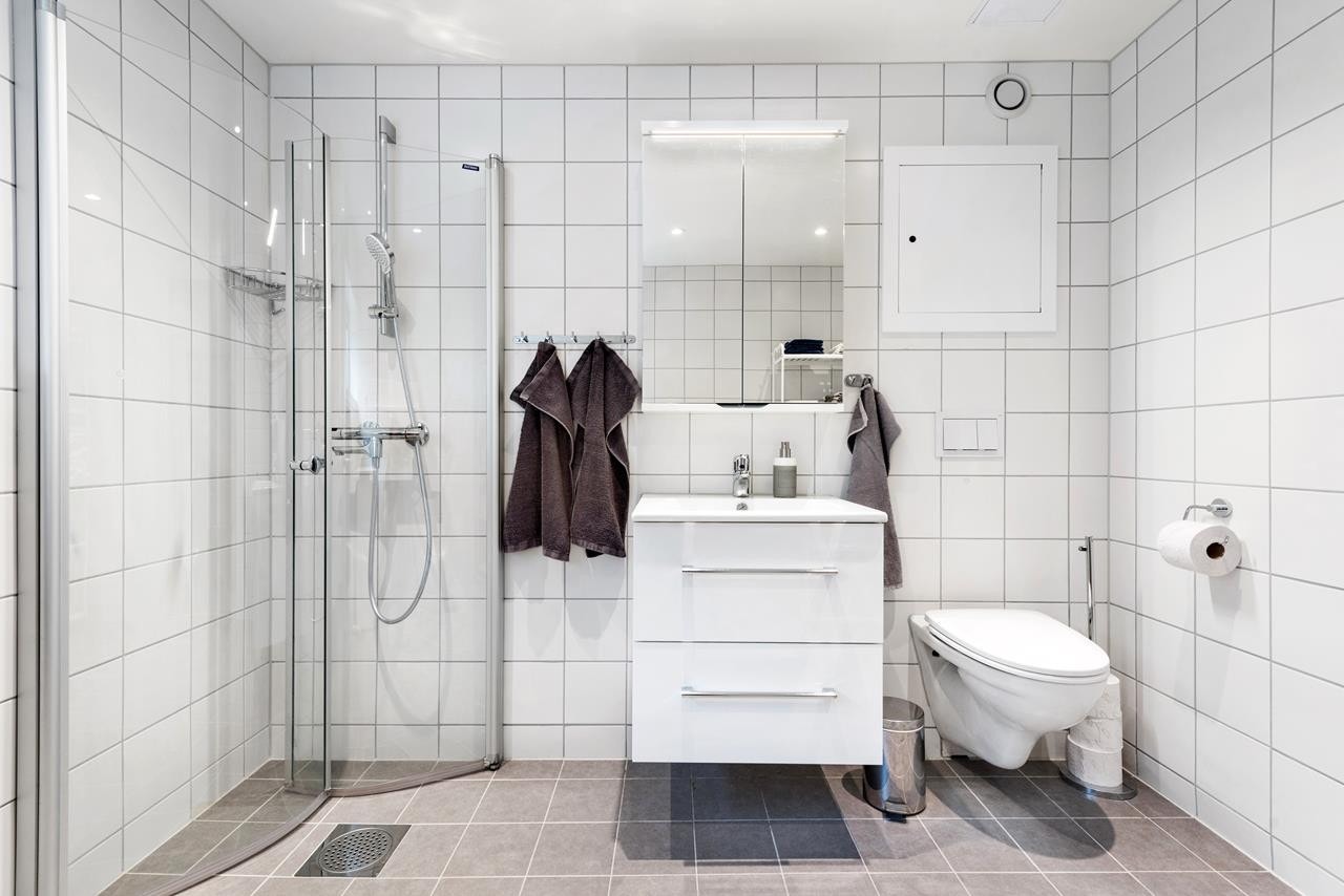 Badet er meget romslig og er innredet med dusjplass, servant med skuffeinnredning, speilskap med belysning og vegghengt wc Galleribilde