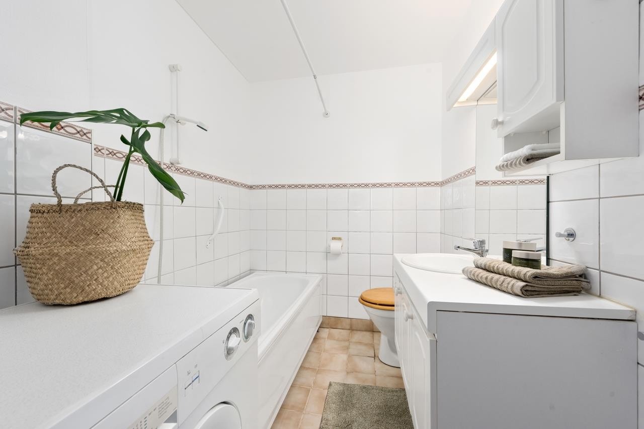 Delvis flislagt bad med badekar og opplegg for vaskemaskin Galleribilde