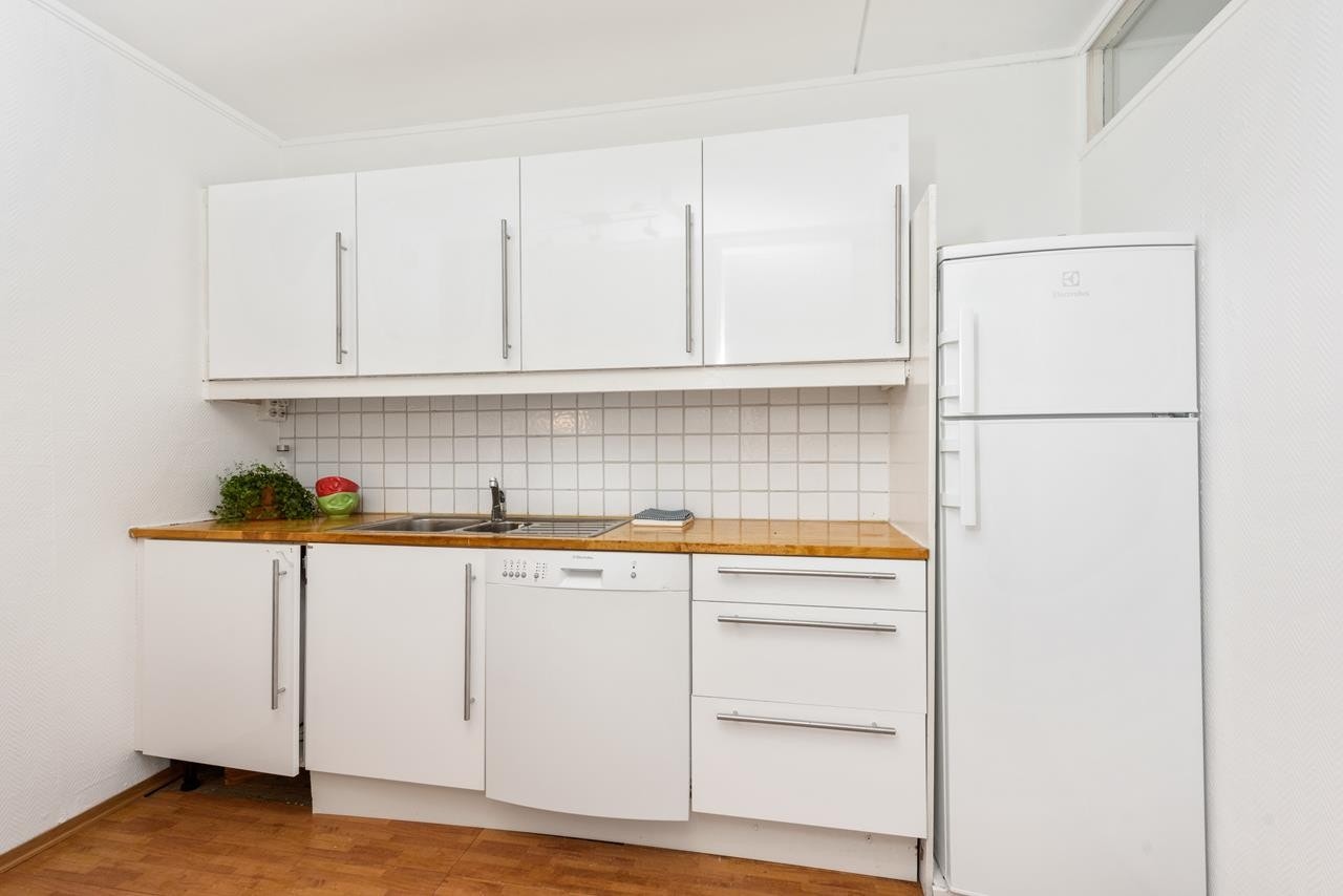 Kjøkkenet har moderne fronter, heltre benkeplate og opplegg for oppvaskmaskin Galleribilde