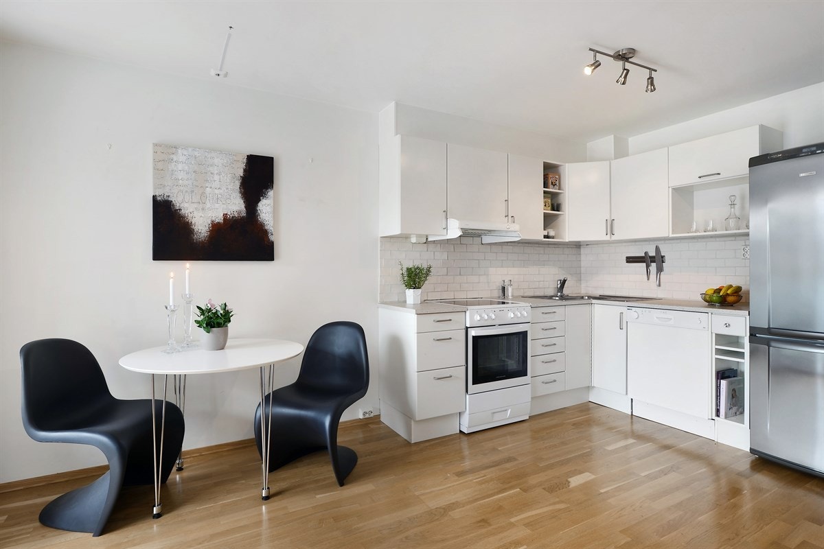 Kjøkkeninnredningen er tidsriktig med hvite, slette fronter og laminert benkeplate med nedfelt dobbel oppvaskkum. Galleribilde